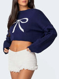 Close-up of a navy blue cropped sweater with a white bow graphic.