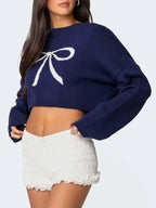 Close-up of a navy blue cropped sweater with a white bow graphic.