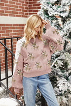 Woman touching her hair while wearing a pink reindeer sweater