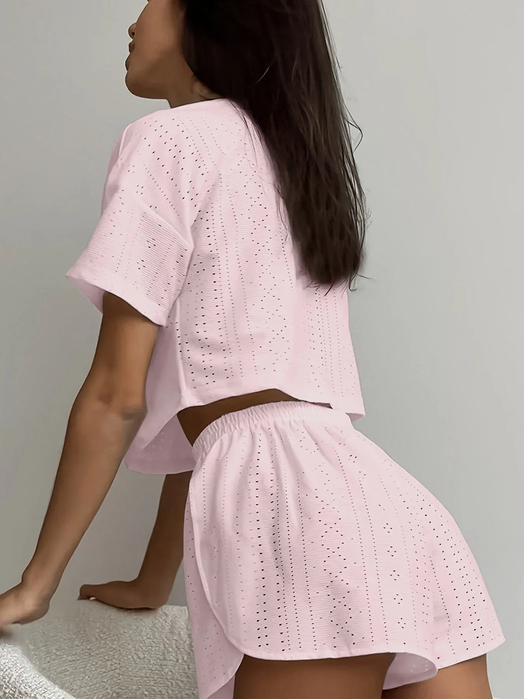 Woman wearing a pink cropped eyelet t-shirt and matching pink eyelet shorts