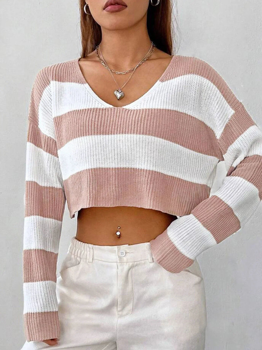 Close-up of a woman's torso wearing a pink and white striped cropped knit sweater, showing the v-neckline.
