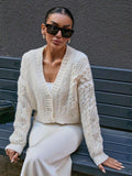Close-up of a woman wearing a cream cable knit cropped cardigan with pearl buttons and sunglasses.