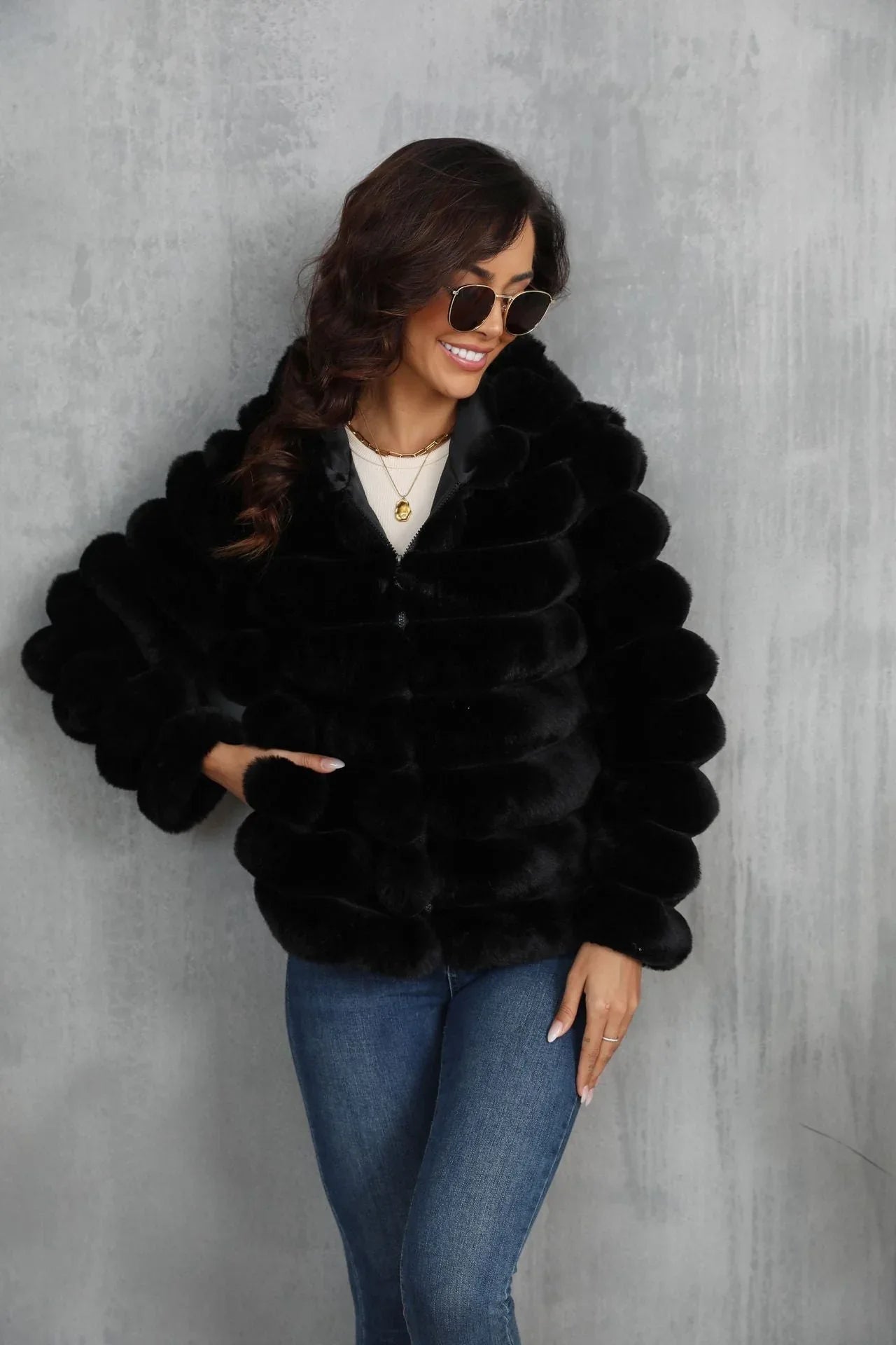 Woman wearing a black hooded faux fur jacket with horizontal stripe pattern and side pockets.