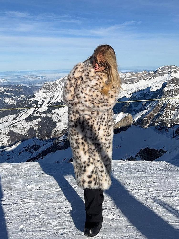 Woman wearing a long leopard print faux fur coat standing in the snow.