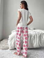 Back view of a woman wearing white top with ruffled sleeves and pink heart print pajamas