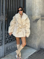 Woman posing in a cream faux fur jacket, highlighting the garment's silhouette and material.