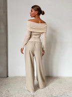 Back view of a woman in a beige off-the-shoulder sweater with long sleeves.
