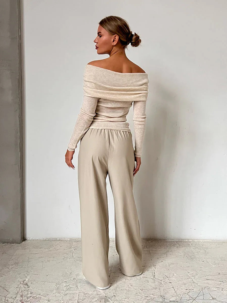 Back view of a woman in a beige off-the-shoulder sweater with long sleeves.