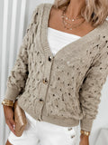 Close-up of the button-down front of a beige open-knit cardigan.