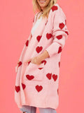 Side profile of a woman with her hands in the pockets of a pink heart print cardigan.