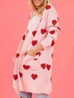 Side profile of a woman with her hands in the pockets of a pink heart print cardigan.
