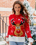 Woman wearing a red Christmas sweater with a reindeer graphic and snowflake print.