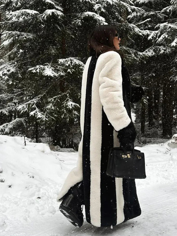 Rear view of a woman in a black and white striped long faux fur coat in a snowy forest.