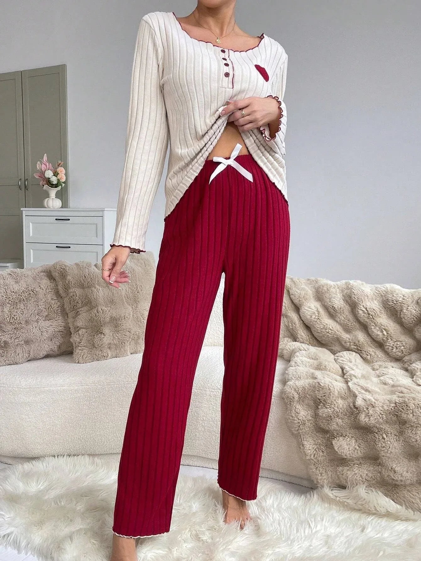 Woman showing the drawstring waist of red ribbed knit pants worn with a cream top.