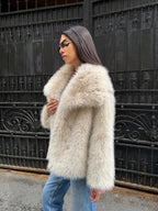 Woman wearing an oversized lapel faux fur jacket in off-white