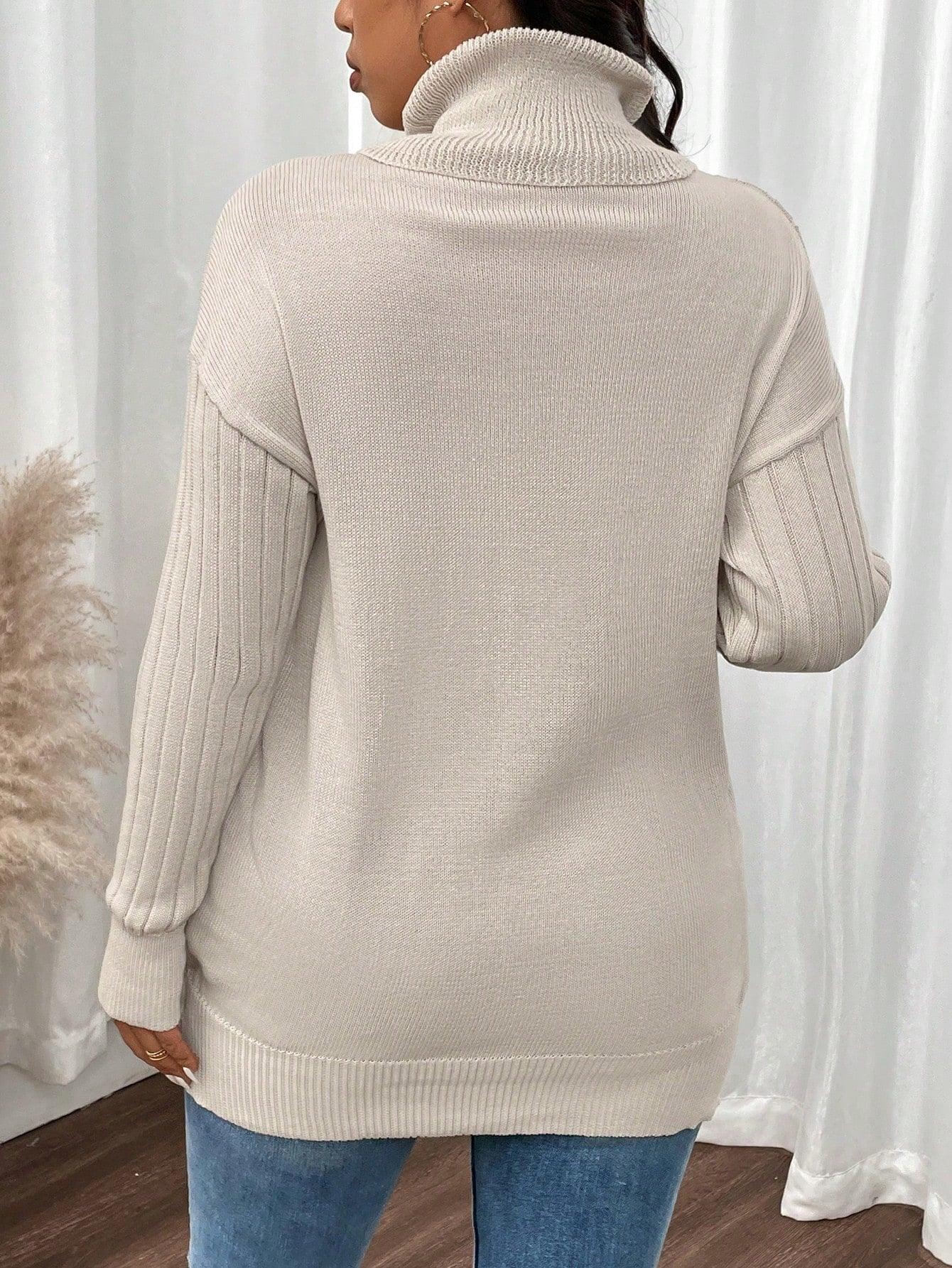 Back view of a woman wearing a cream ribbed knit turtleneck tunic sweater.