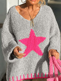 Close-up of a woman's chest showing the gray knit texture and pink star graphic on the sweater.