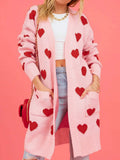Woman in a pink heart patterned cardigan, styled with a white crop top and denim.