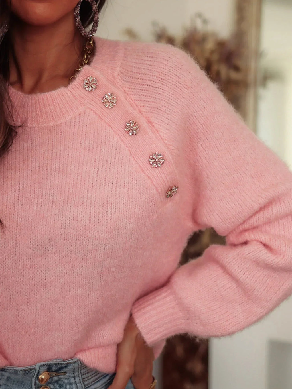 Close-up of the jeweled buttons on a pink knit sweater shoulder