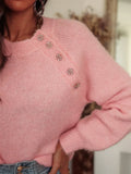 Close-up of the jeweled buttons on a pink knit sweater shoulder