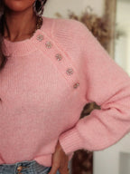 Close-up of the jeweled buttons on a pink knit sweater shoulder