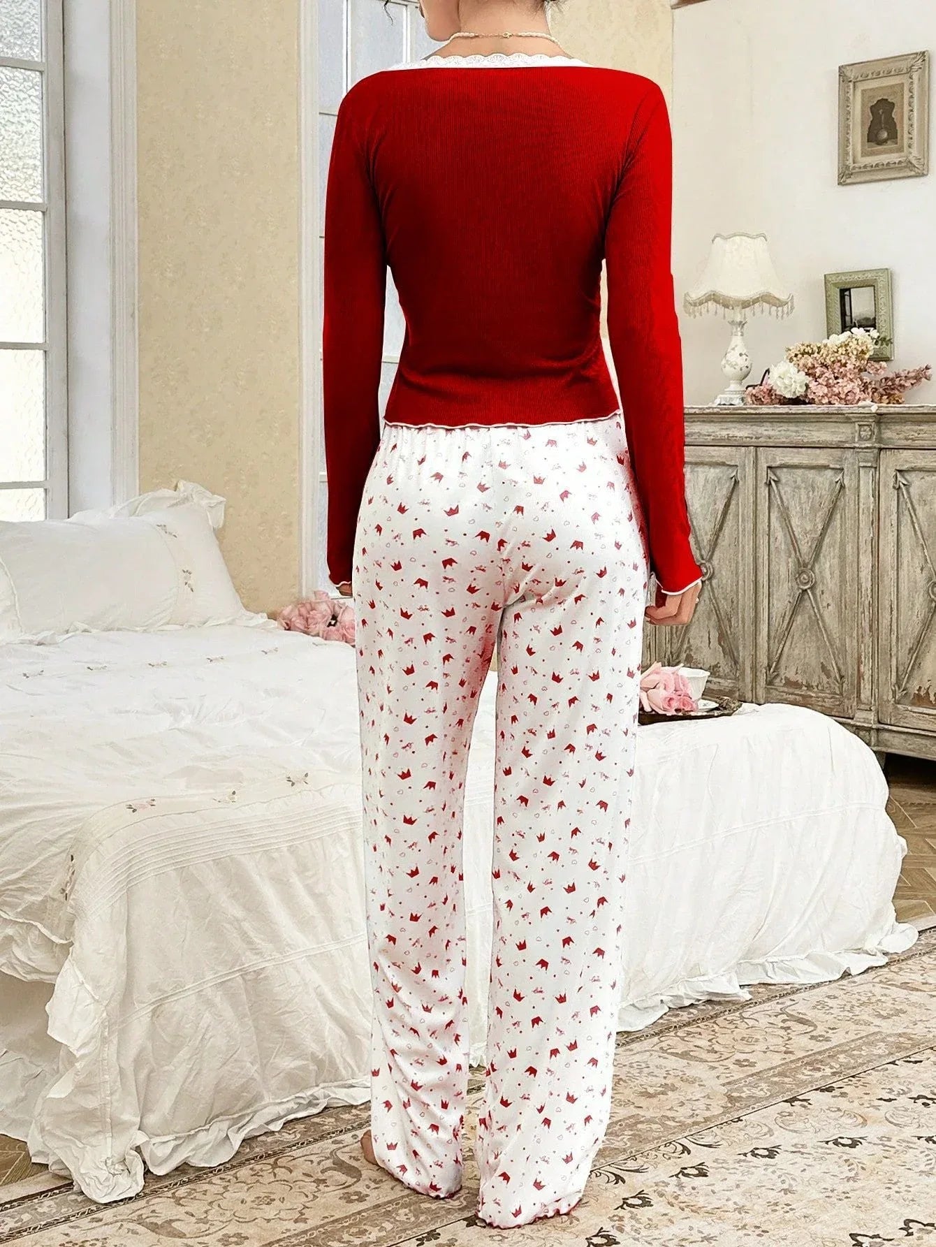 Rear view of woman in red long-sleeve top and white patterned pajama pants.