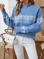Woman in a blue Nordic snowflake mock neck sweater holding a white clutch