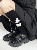 Close-up of black knee-high socks featuring a plush panda accessory attached by a silver chain.