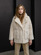 Front view of the model wearing the cream faux fur coat, showcasing the open lapels and pockets.