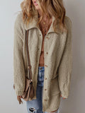 Woman in a beige textured knit cardigan, brown top, and blue jeans, accessorized with a crossbody bag.