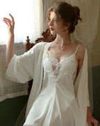 Woman wearing a cream satin nightgown with lace trim and spaghetti straps, paired with a matching robe.