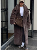 Woman wearing a long, brown faux fur coat and black leggings.