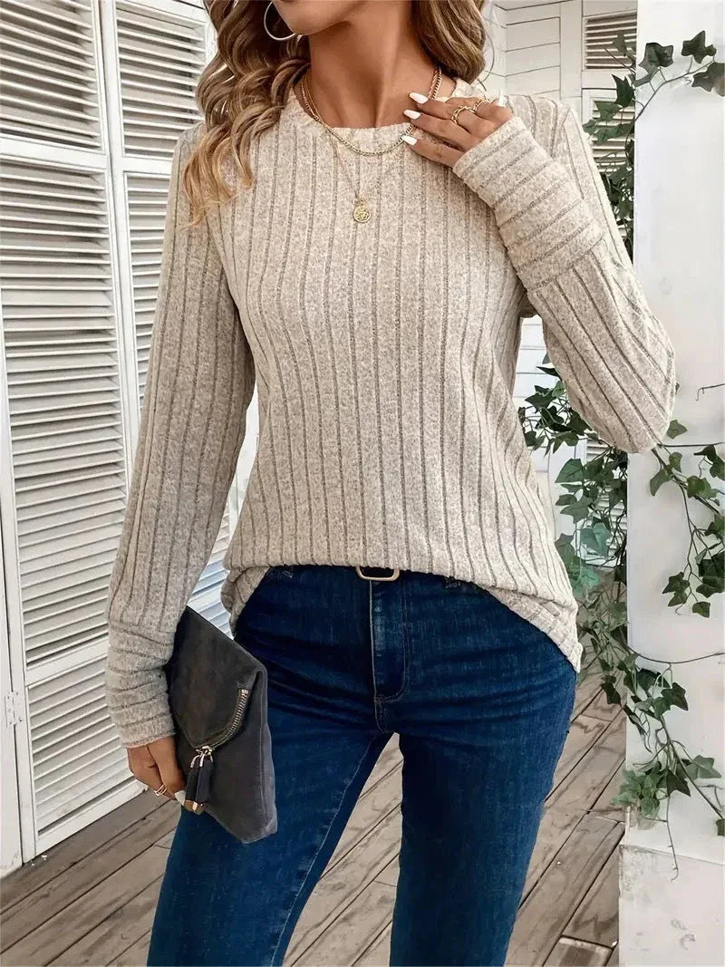 Woman holding a clutch in a beige ribbed knit top