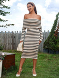 Woman with a handbag wearing a beige and black striped off-the-shoulder midi dress with long sleeves.