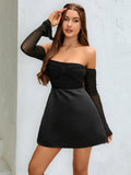 Woman wearing a black off-the-shoulder dress with sheer sleeves, holding her hair