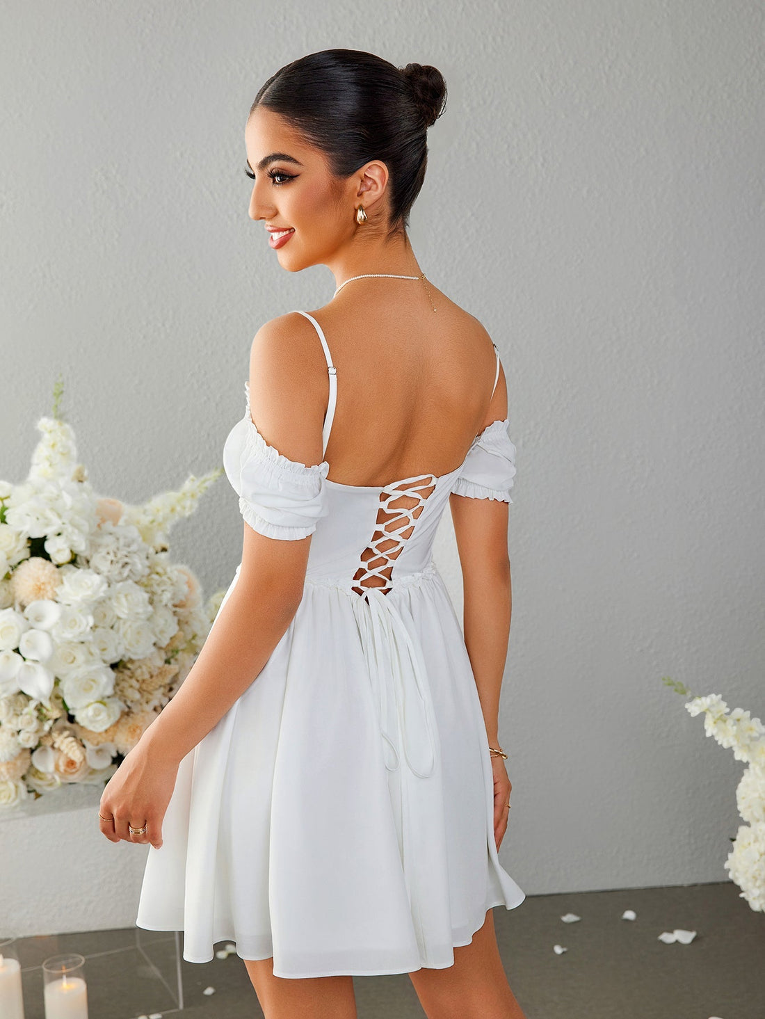 Woman wearing a white off-the-shoulder ruched bodice dress with puff sleeves and a full skirt.