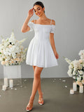 Full body shot of a woman in a white off-the-shoulder dress with a fit and flare silhouette.