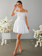 Full body shot of a woman in a white off-the-shoulder dress with a fit and flare silhouette.