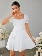 Woman smiling and adjusting her white off-the-shoulder dress with puff sleeves.
