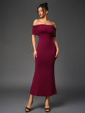 Full body shot of a woman in an elegant off-the-shoulder maroon evening dress.