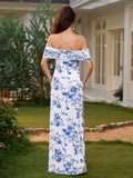 Back view of a woman in a white maxi dress with a blue floral print and off-the-shoulder neckline.