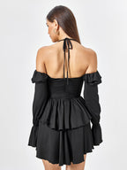 Back view of a woman in a black tiered dress with long sleeves.
