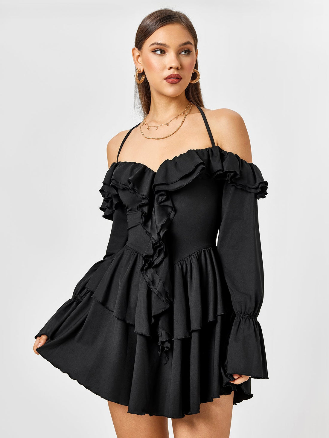 Woman wearing a black off-the-shoulder dress with ruffle details and a halter neck.