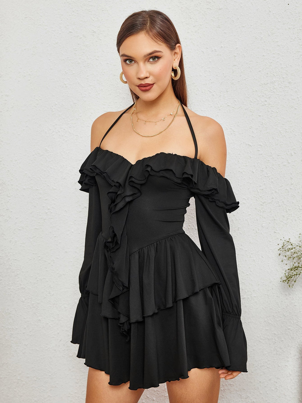 Model posing in a black off-the-shoulder dress with tiered ruffles.