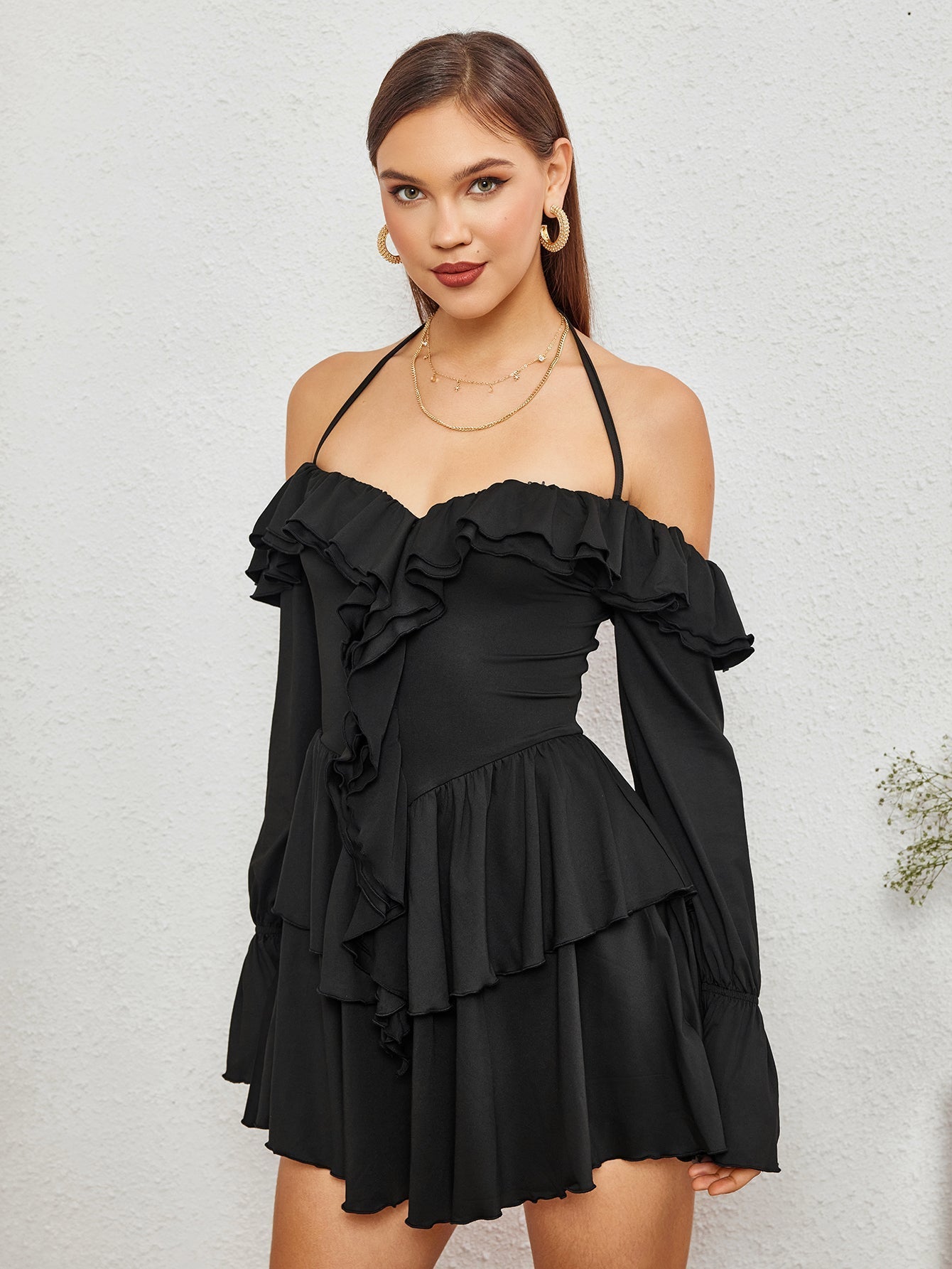 Model posing in a black off-the-shoulder dress with tiered ruffles.