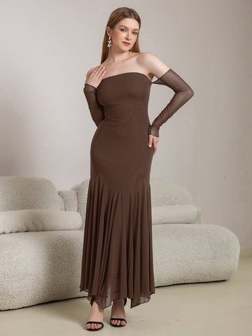 Woman wearing a long brown off-the-shoulder dress with sheer long sleeves and a mermaid hem