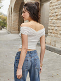 Back view of a woman in a white off-the-shoulder ruched crop top and blue jeans