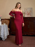 Woman in a red sparkle mermaid gown with off-the-shoulder long sleeves smiling.