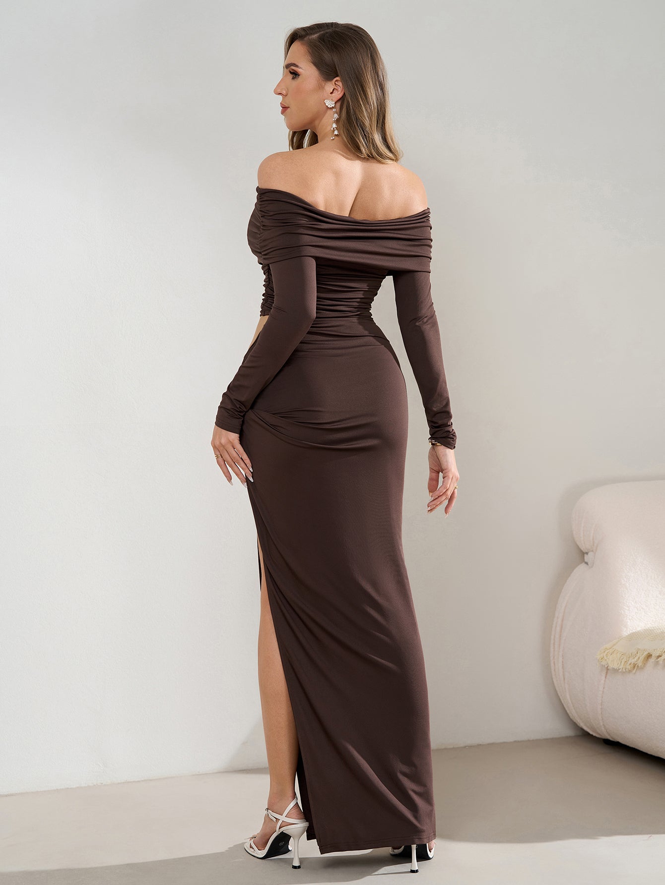 Back view of a woman in a brown off-the-shoulder ruched maxi dress with a side cutout and high slit