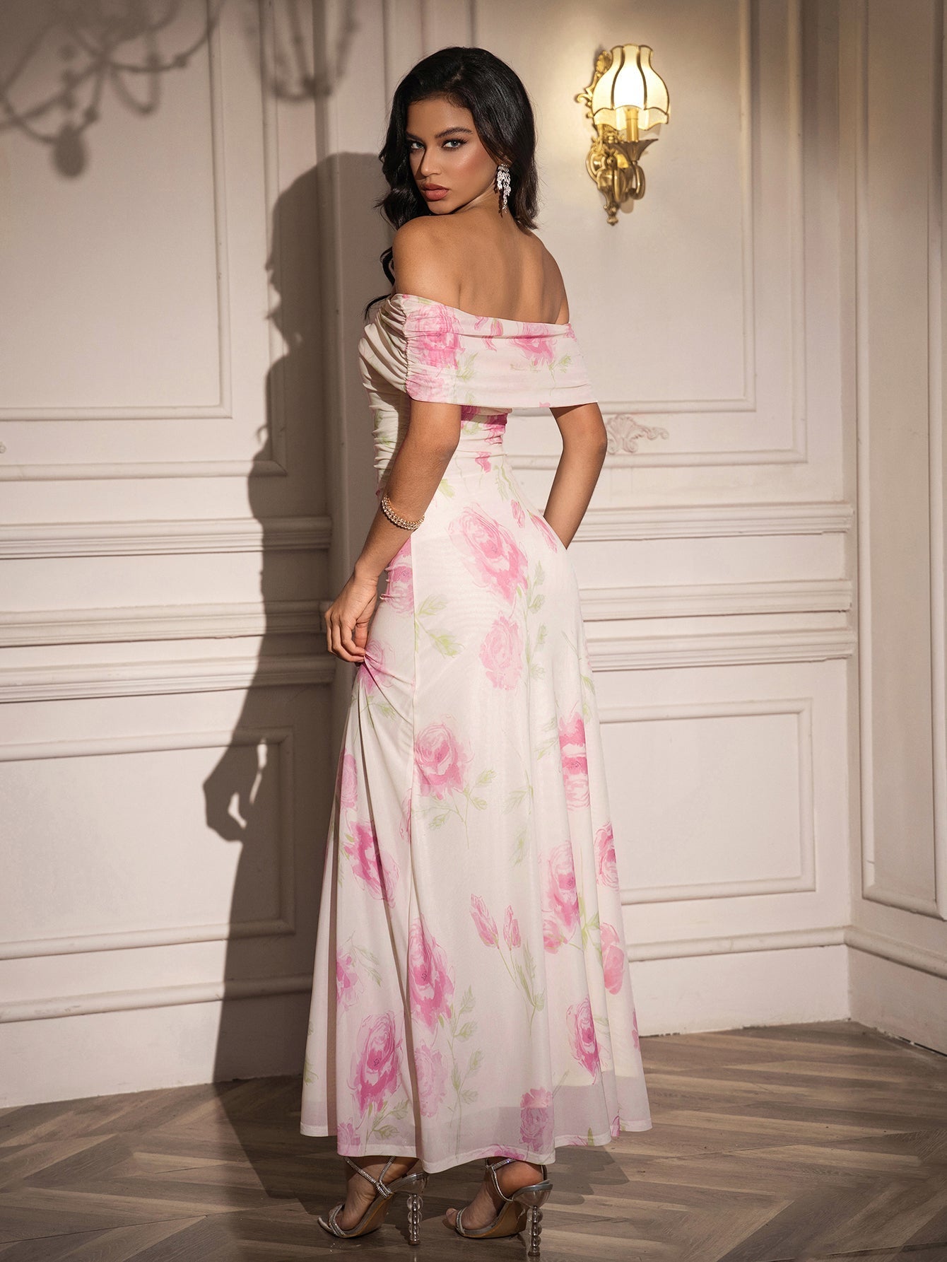 Rear view of a woman in a white off-the-shoulder maxi dress with a pink floral print.